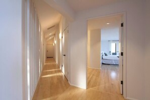A hallway with wooden flooring leading to a bedroom with a bed and a nightstand. - Modern Panoramic Hillside Escape (Santa Rosa)