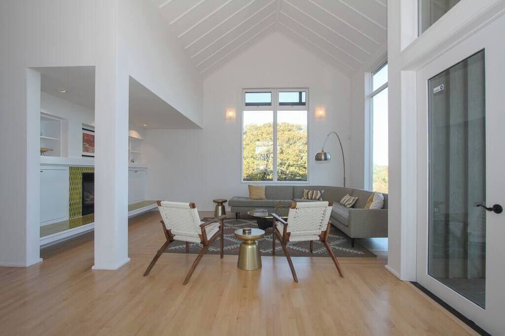 Een ruime woonkamer met een hoge plafond, een open haard, een bank en een eettafel.