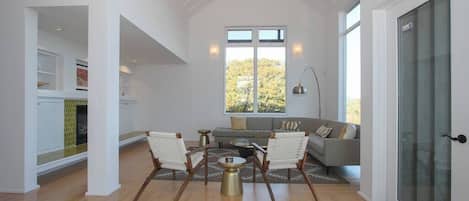 A spacious living area with a high ceiling, a fireplace, a sofa, and a dining table.