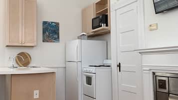 A compact kitchen with white cabinetry, a built-in microwave, and a small countertop.