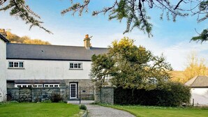 A two-story house with a stone facade, a gravel driveway, and a well-maintained lawn.