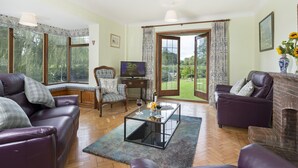 Ein Wohnzimmer mit Ledersofas, einem Glastisch, einem Fernseher und einem Kamin.