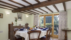 Ein Esszimmer mit Holztisch, gedeckt für vier Personen, umgeben von Stühlen und Blick durch eine Glastür.