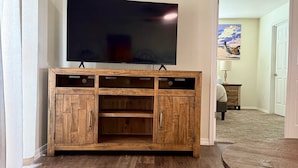 Ein Wohnzimmer mit einer Holz-Unterhaltungsecke, einem an der Wand montierten Flachbildfernseher und einem runden Couchtisch.