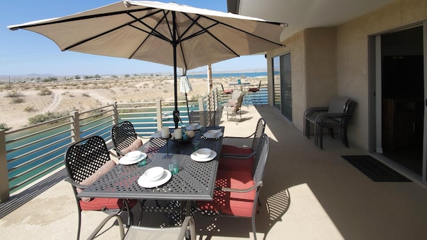 Ein Balkon mit Tisch für zwei Personen, Sonnenschirm und Blick auf eine Wüstenlandschaft.