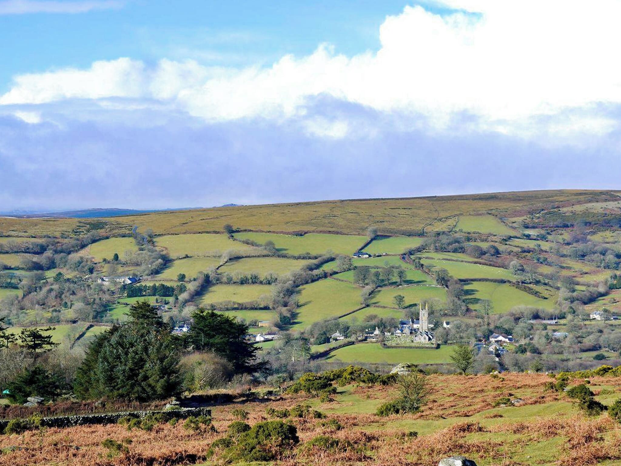 A rural landscape with rolling hills, a stone wall, and a small village with a prominent church.