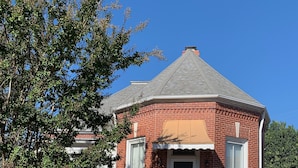 Een bakstenen huis met pannendak, een veranda en een pad dat naar de ingang leidt.