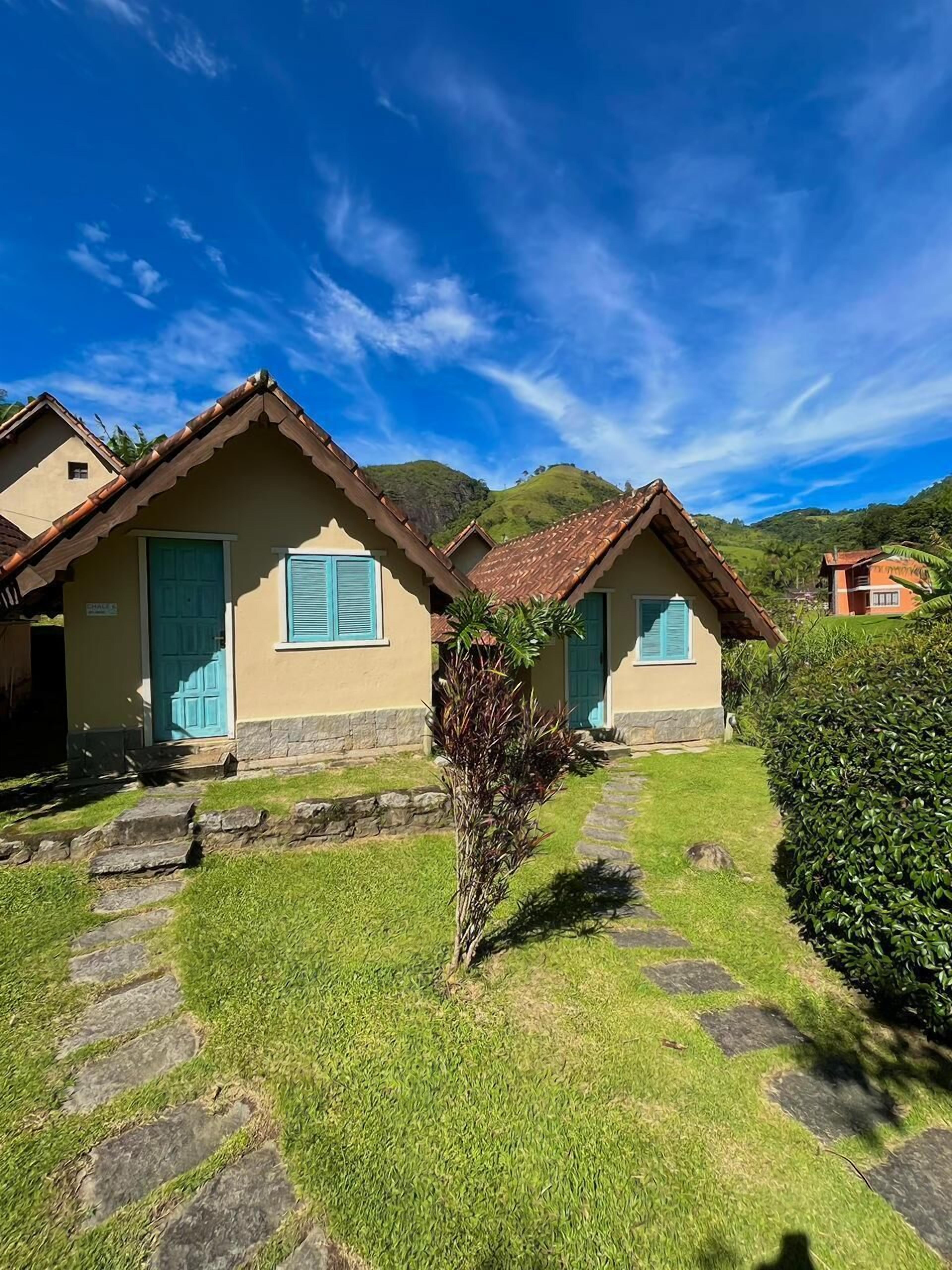 Una hilera de casas de dos pisos con tejados de tejas, un sendero de piedra y un árbol pequeño en primer plano.