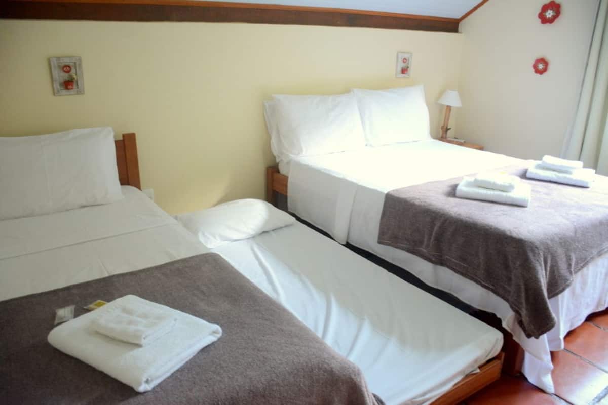Ein Hotelzimmer mit zwei Betten, jeweils mit weißer Bettwäsche und einer braunen Decke. Zwei Nachttische mit Lampen und Wandblumen sind ebenfalls vorhanden.