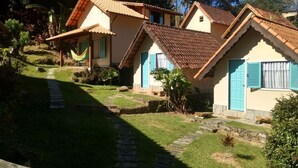 A row of two-story houses with tiled roofs, a stone pathway, and lush greenery. - Pousada dos Anjos (Nova Friburgo)