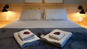 A neatly made bed with two pillows, a headboard with framed botanical prints, and two bedside lamps. - Pousada dos Anjos (Nova Friburgo)