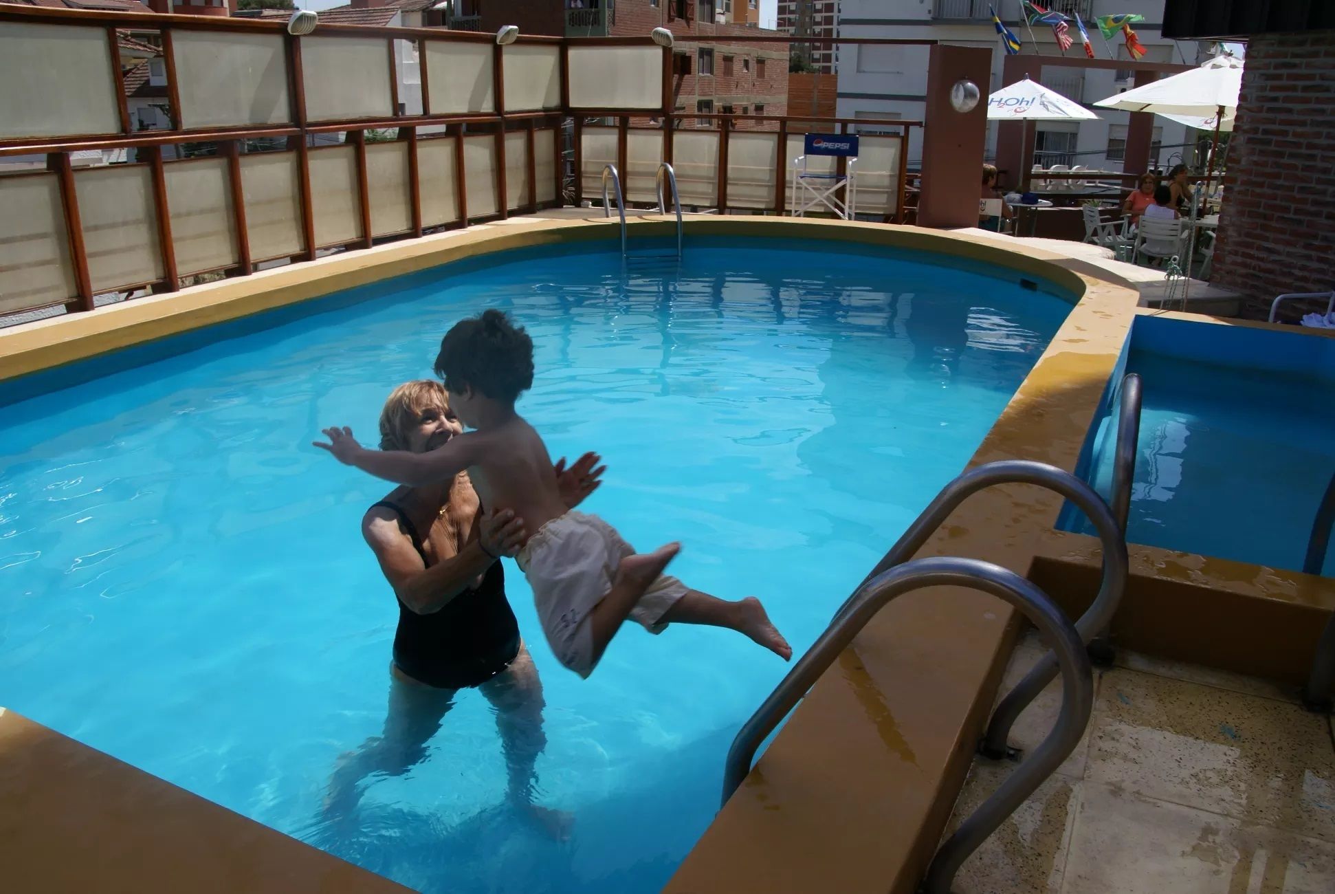 Una piscina con una escalera metálica y una valla de seguridad.