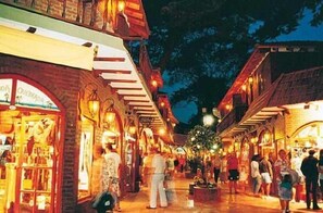 A bustling outdoor shopping area with brick buildings and wooden walkways. - Hotel Gran International (Villa Gesell)