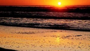 A sunset over the ocean with waves approaching the shore. - Hotel Gran International (Villa Gesell)