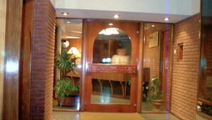 A lobby with a polished floor, a reception desk, and potted plants. - Hotel Gran International (Villa Gesell)