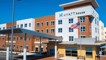 Hyatt House features a striking brick and white facade with large windows and a covered outdoor area with benches.
