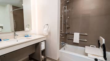 A modern bathroom with a bathtub, a shower, a sink, and a mirror.
