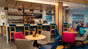 A bar area with multiple seating options, a bar counter, and a television screen. - Hyatt House Nashville/Franklin/Cool Springs (Franklin)