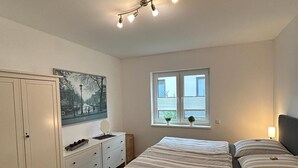 Une chambre à coucher avec un lit, une commode, une fenêtre et un tableau au mur.