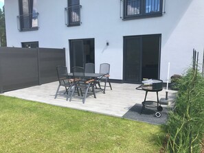 An outdoor patio with a table and chairs, a grill, and a fence. - TOP apartment near Berlin, very easy access (Bestensee)