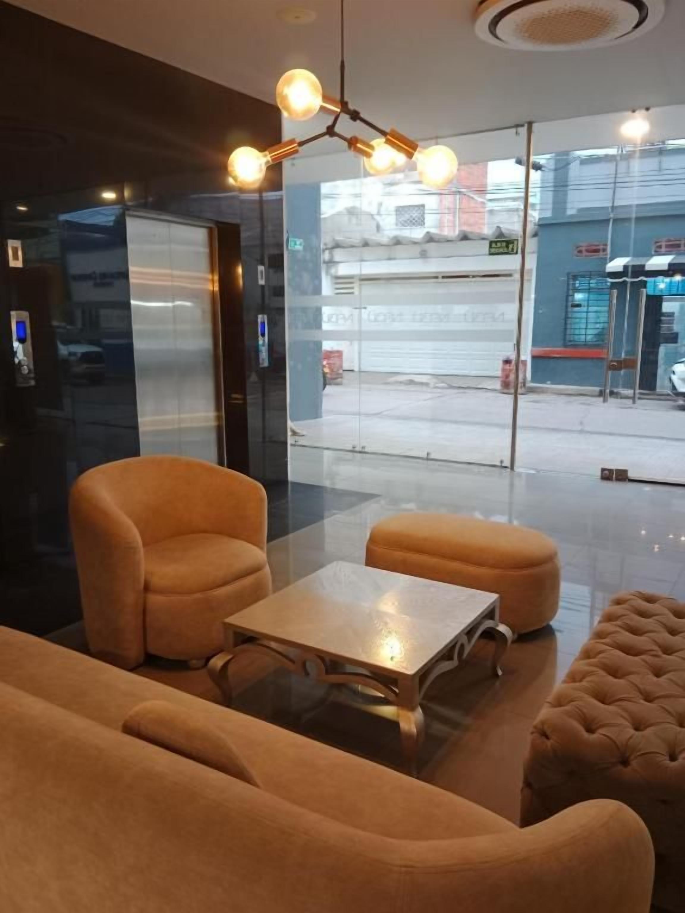 A modern interior with a glass partition, a sofa, a coffee table, and a hanging light fixture.
