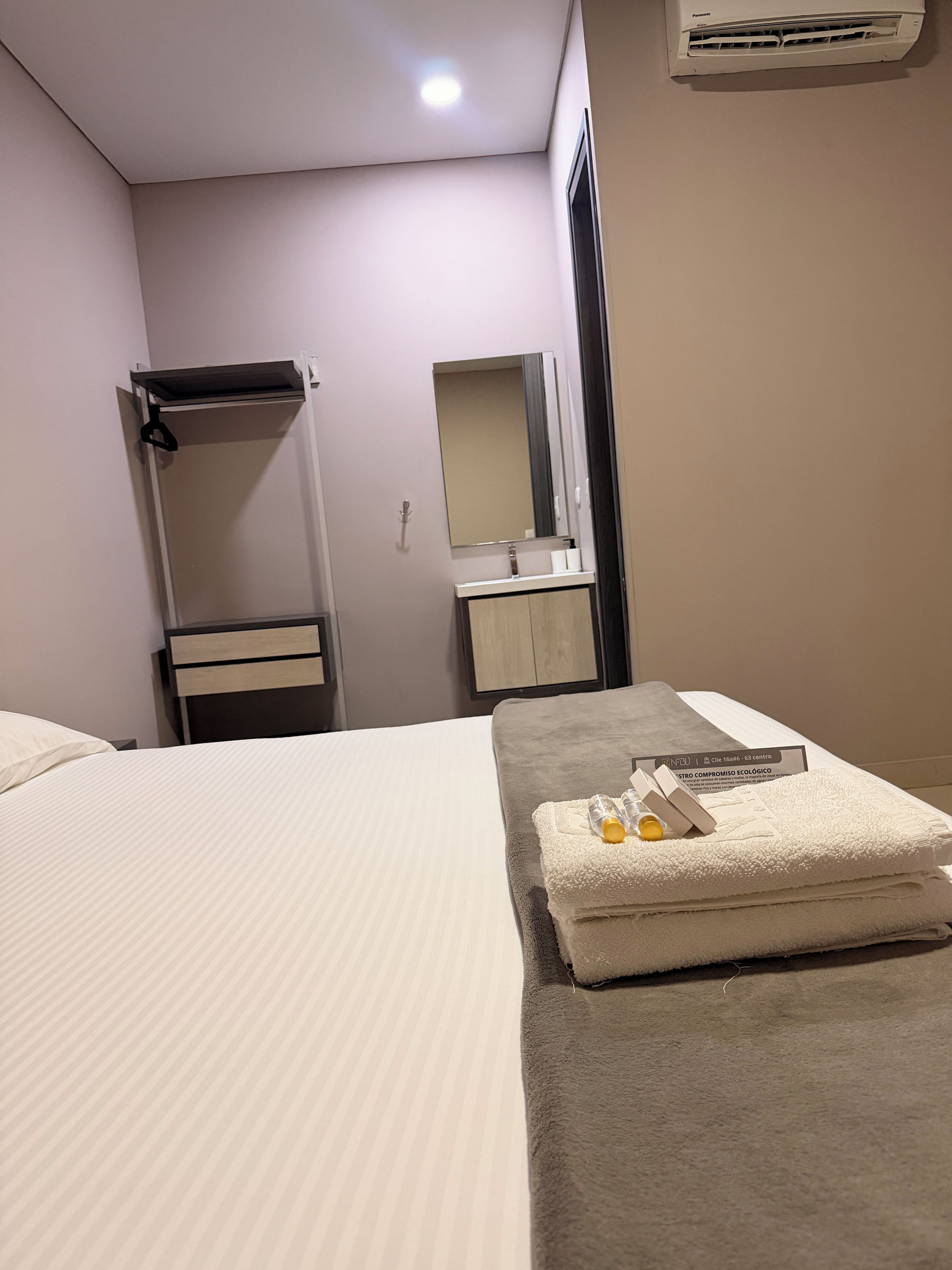 A hotel room with a bed, a towel, and a mirror.