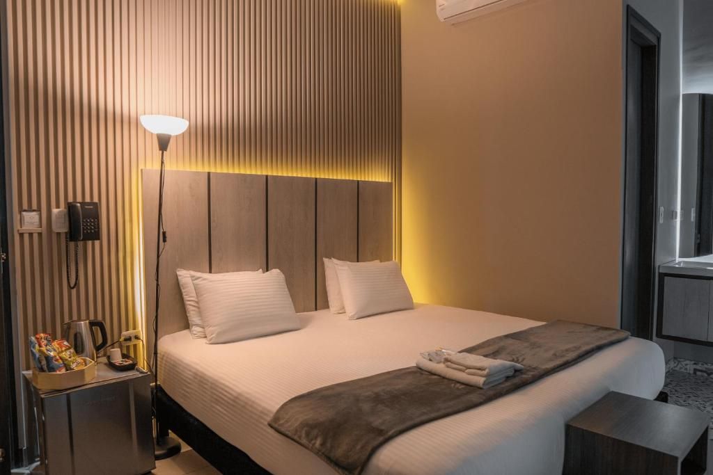 A hotel room with a bed, bedside table, lamp, and a window.