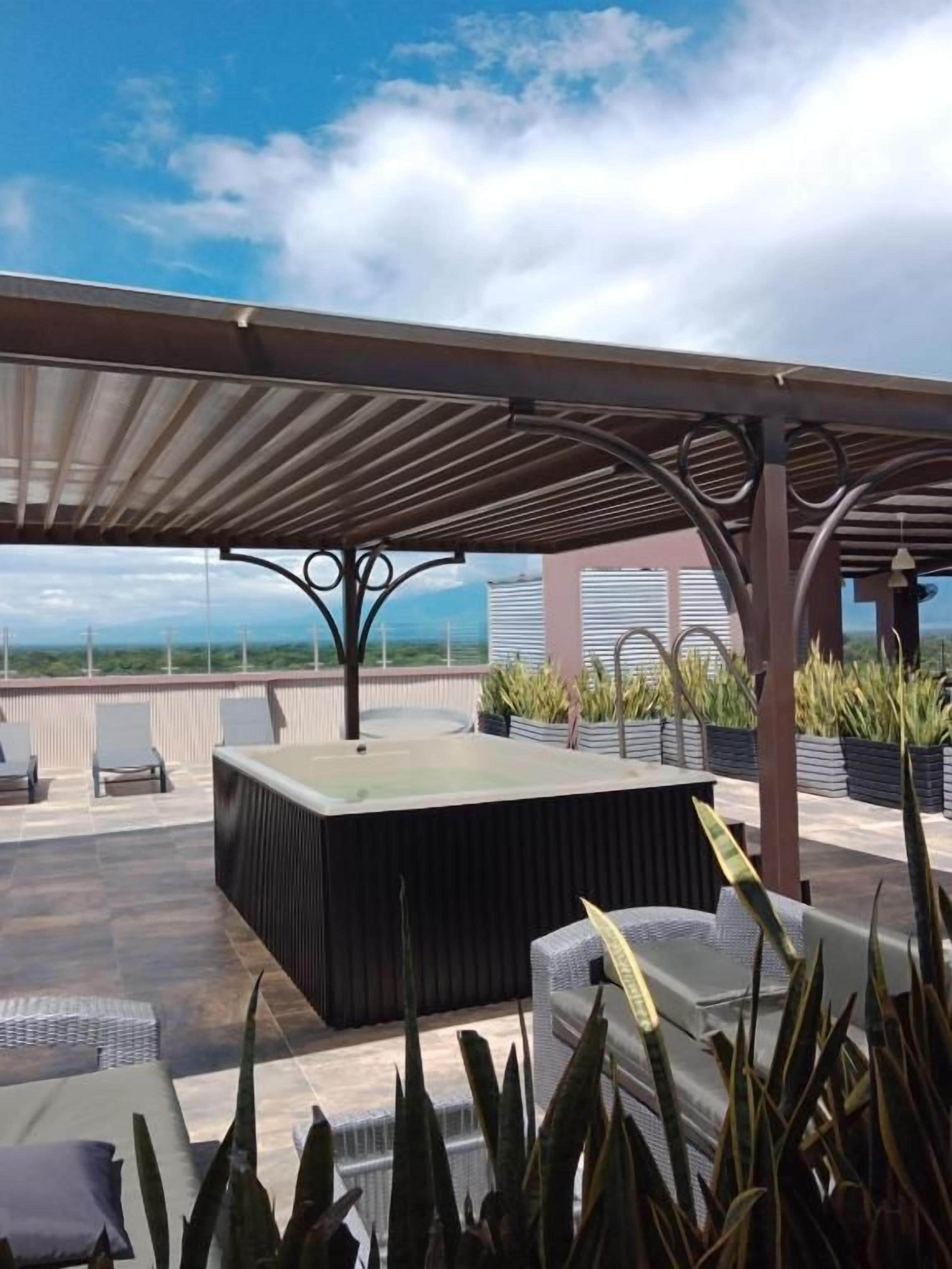 An outdoor seating area with a pergola, a fire pit, and potted plants.