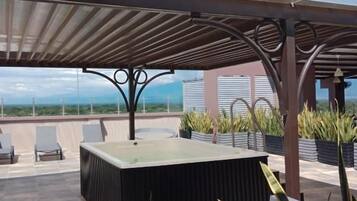 An outdoor seating area with a pergola, a fire pit, and potted plants.