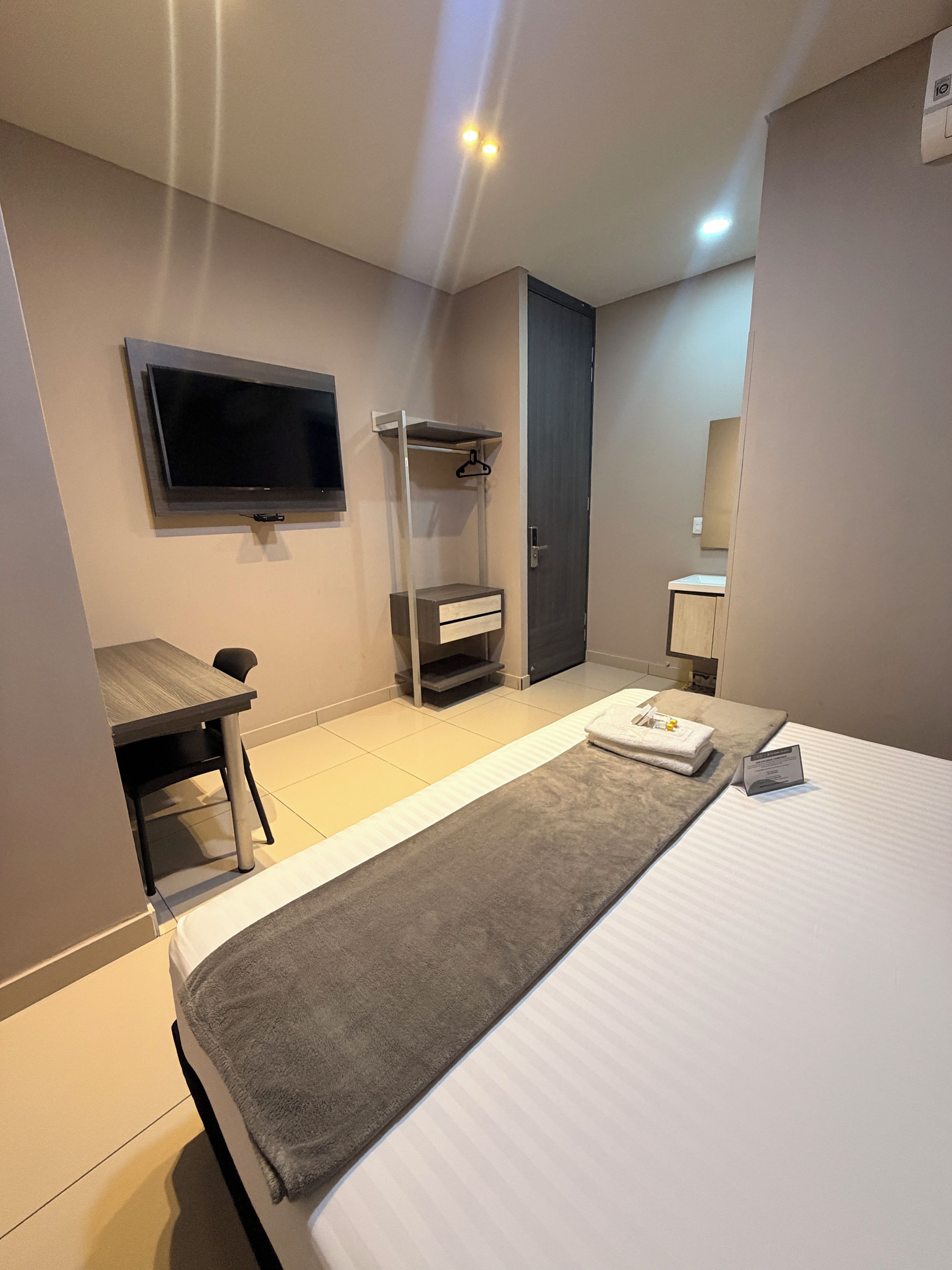 Une chambre d’hôtel comprenant un lit, un bureau, une télévision, une armoire et une salle de bain.