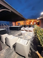 Un espacio al aire libre con patio amoblado, jacuzzi e iluminación ambiental.