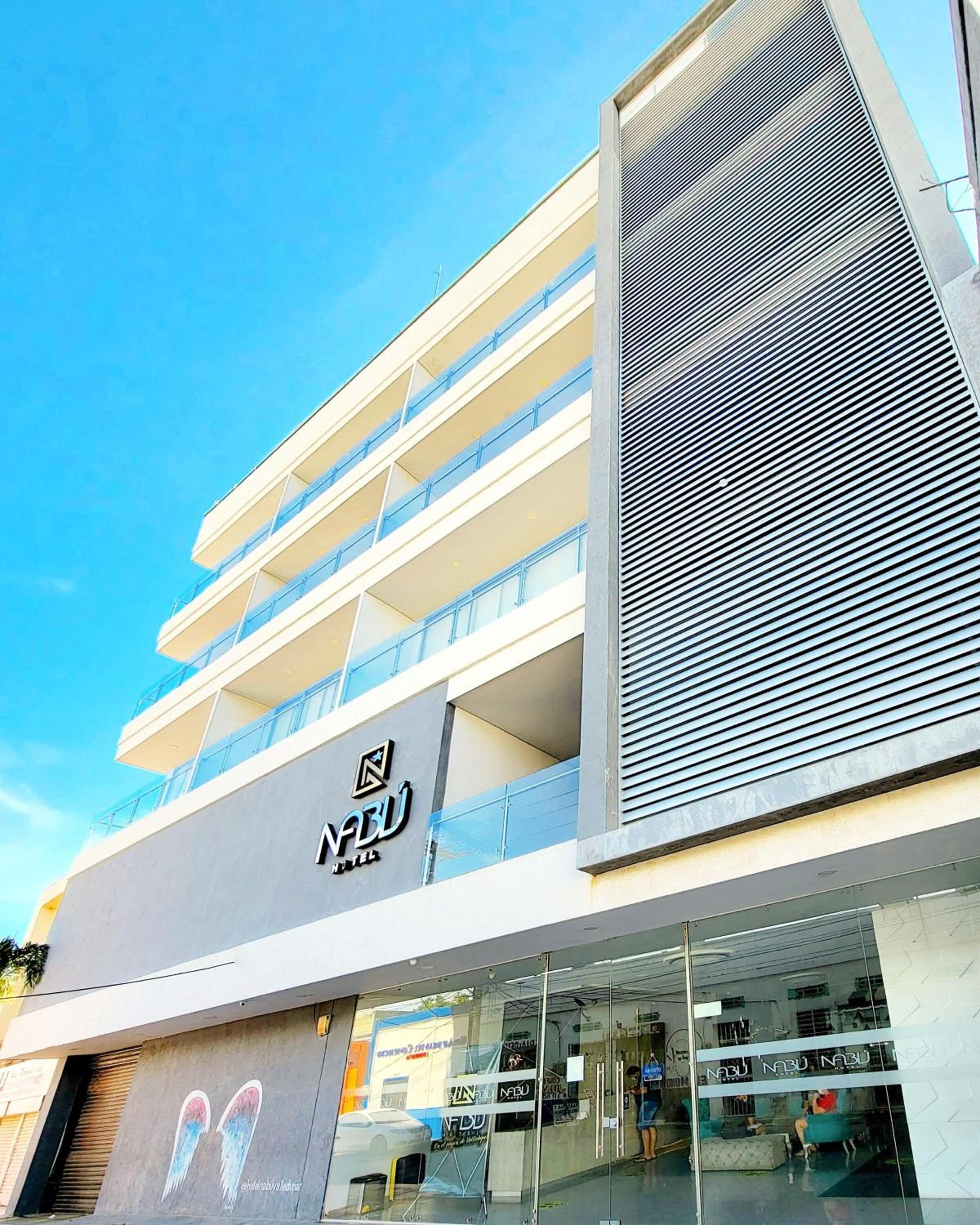 Un hotel con fachada moderna, varios balcones y cielo despejado.