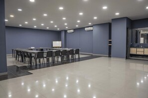 Un salón de conferencias con una larga mesa, sillas y una pizarra.