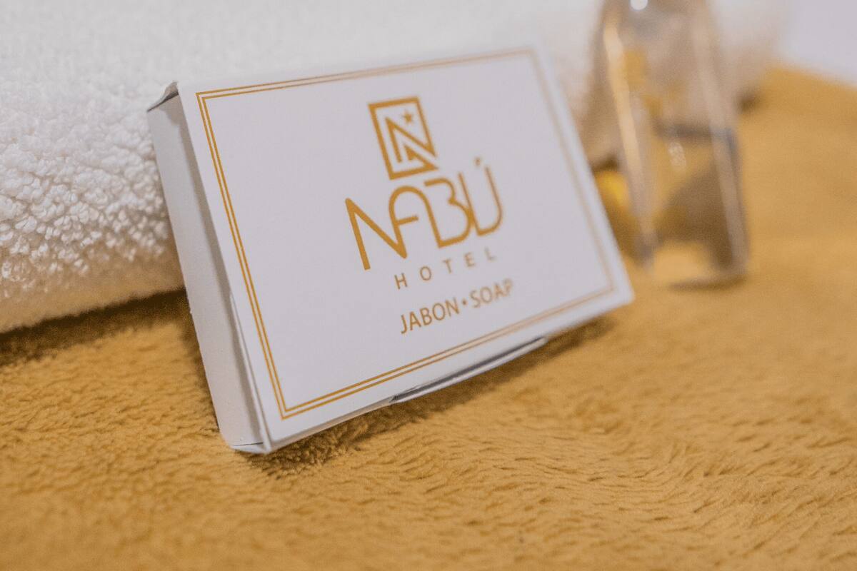 A white box with gold lettering and a bottle of liquid soap on a textured surface.