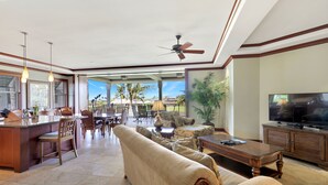Amplia sala de estar con cocina, comedor y un televisor grande.