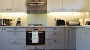 Una cocina moderna con armarios grises, horno integrado, estufa a gas y un tostador.