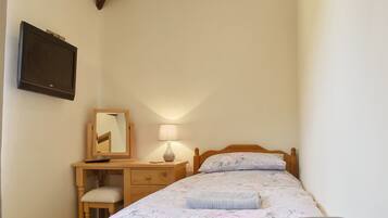 A bedroom with a bed, a desk, a chair, a lamp, and a mirror.