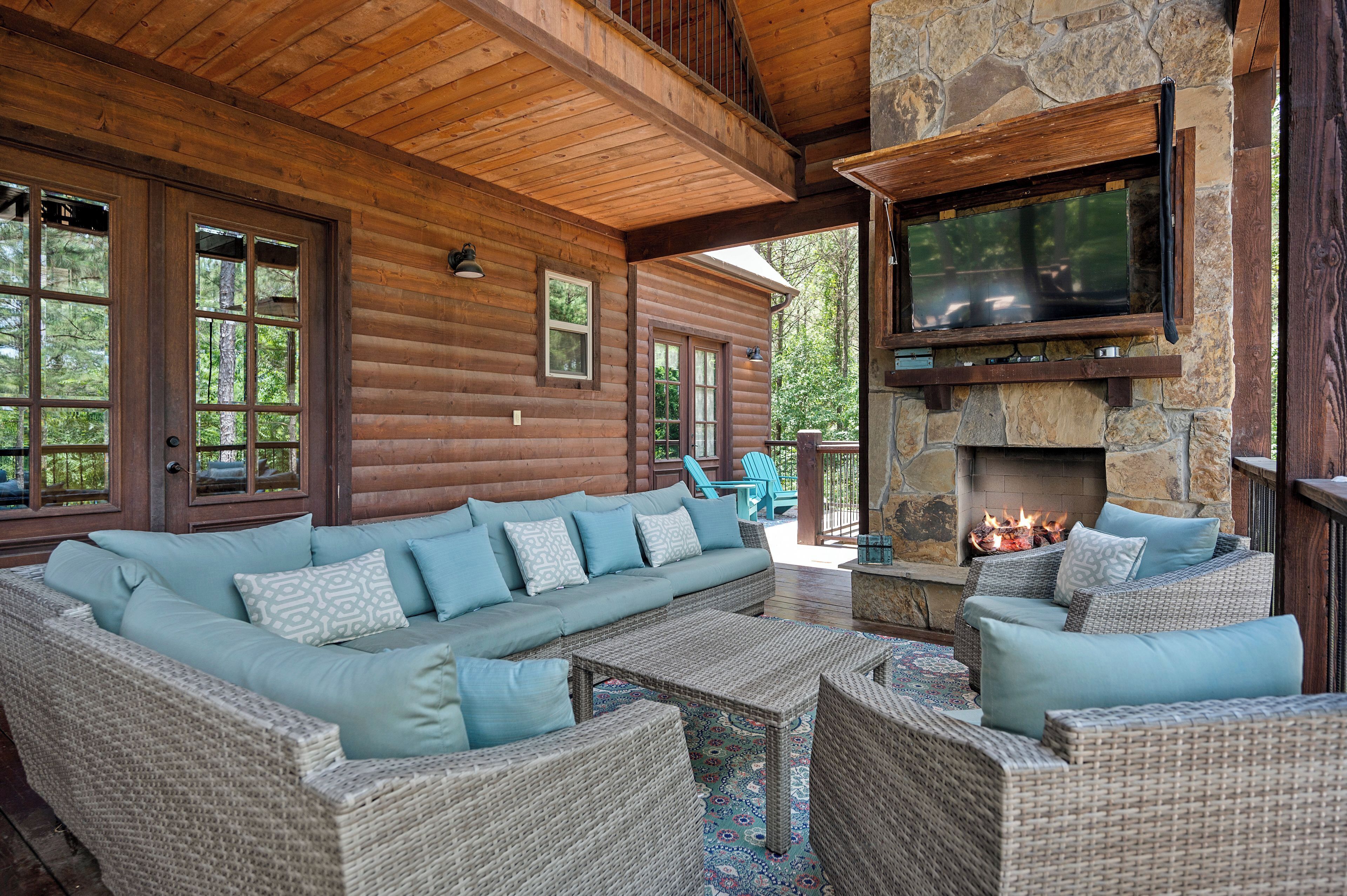 A log cabin with a stone fireplace, a large sofa, and wicker furniture.