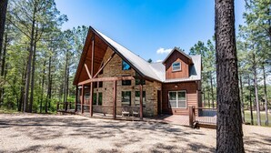 A log cabin with a sloped roof, large windows, and a deck.