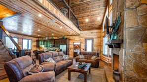 A spacious living room with leather sofas, a coffee table, and a stone fireplace.