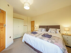 A bedroom with a bed, two bedside tables, a wardrobe, and a ceiling light.