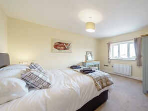 A bedroom with a bed, a bedside table, a window with curtains, a radiator, and a painting on the wall. - 5 bedroom accommodation in Crossway Green, near Stourport-on-Severn (Crossway Green, near Stourport-on-Severn)