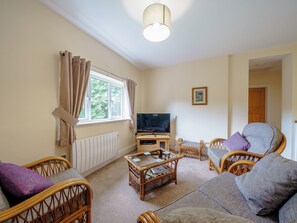 A living room with wicker furniture, a television, and a window with curtains. - 5 bedroom accommodation in Crossway Green, near Stourport-on-Severn (Crossway Green, near Stourport-on-Severn)