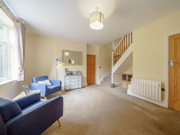 A room with a blue sofa, a white dresser, a mirror, a staircase, and a radiator.