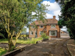 A two-story brick house with a paved driveway, surrounded by trees and a grassy lawn. - 5 bedroom accommodation in Crossway Green, near Stourport-on-Severn (Crossway Green, near Stourport-on-Severn)