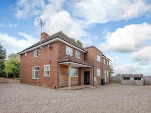 A two-story brick house with a front porch, a garage, and a gravel driveway.