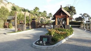 A small pavilion with a sloped roof, surrounded by a landscaped garden with palm trees and a stone pathway leading to it. - 35679 Beach Rd ocean front newly remodeled 2025
 Dana Point Permit STR14-0101 (Dana Point)