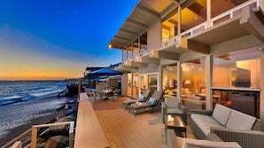 A deck with outdoor seating overlooking a beach, a pool area, and a view of the ocean at sunset. - 35679 Beach Rd ocean front newly remodeled 2025
 Dana Point Permit STR14-0101 (Dana Point)