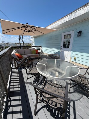 A deck with outdoor furniture, including a table and chairs, and a covered seating area. -  Sleeps 12•Huge PrivateDeck•Beach Gear•Pool Table•Steps to Ocean•Trailer parking (Ormond Beach)