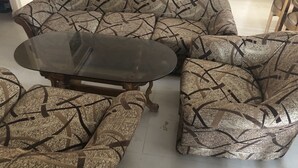 Un saló amb una taula de centre de vidre i sofàs amb dibuixos.